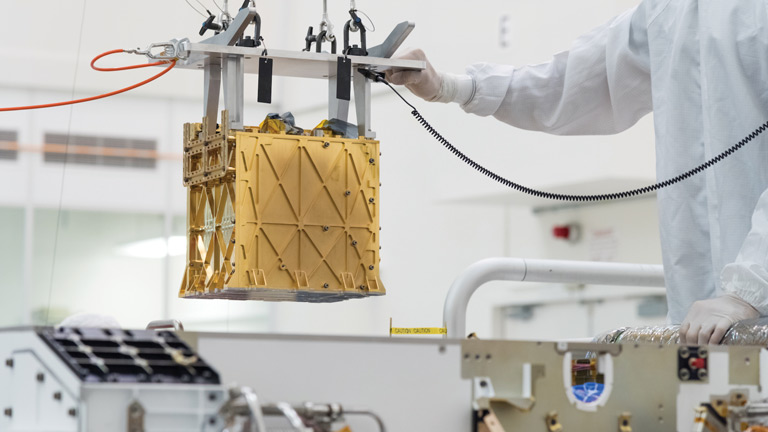 Technicians at NASA’s Jet Propulsion Laboratory lower the Mars Oxygen In-Situ Resource Utilization Experiment (MOXIE) instrument into the belly of the Perseverance rover.